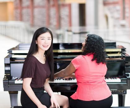 girl sitting with woman on a piano bench