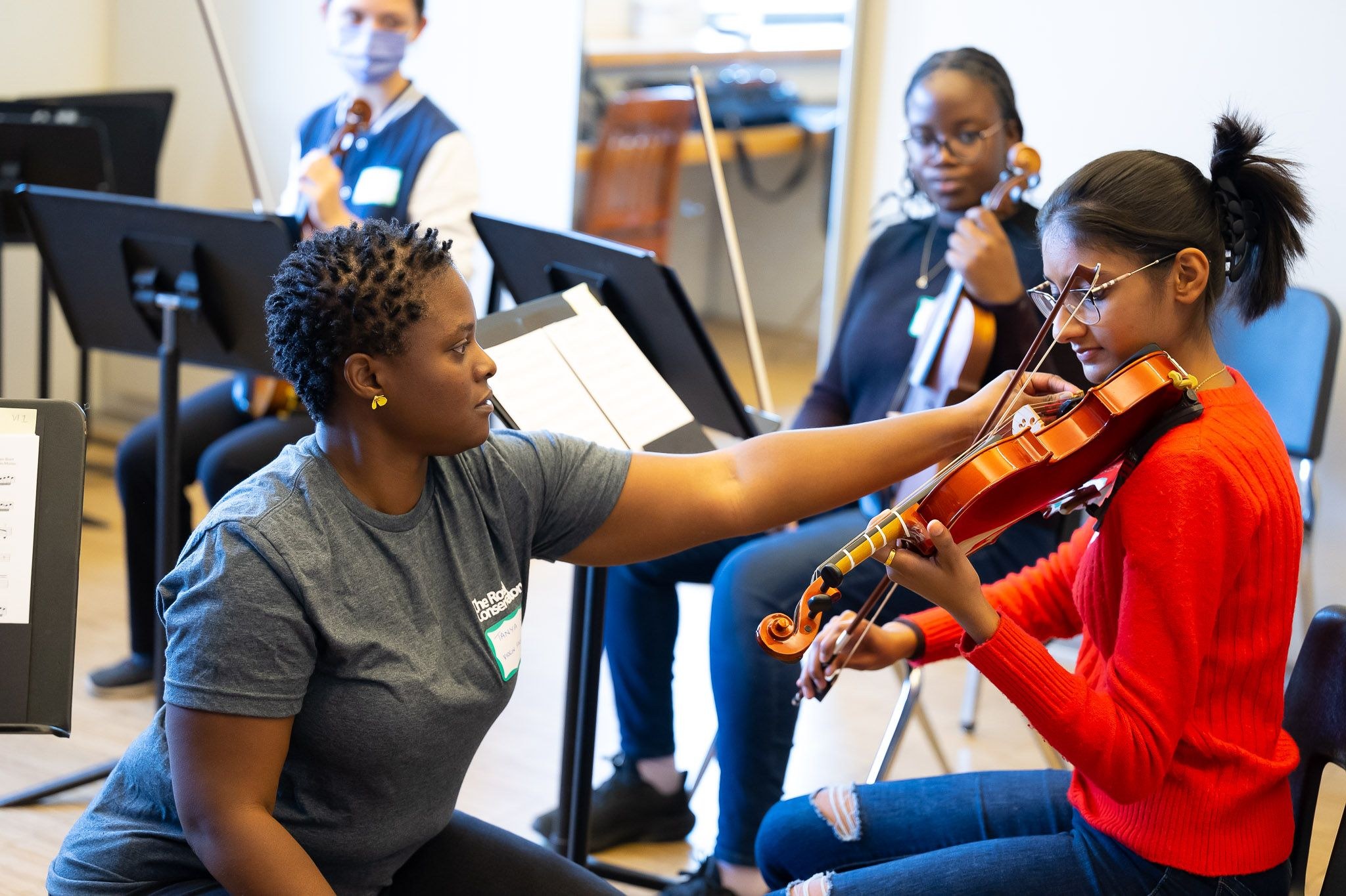 music teacher showing right position to girl playing violin